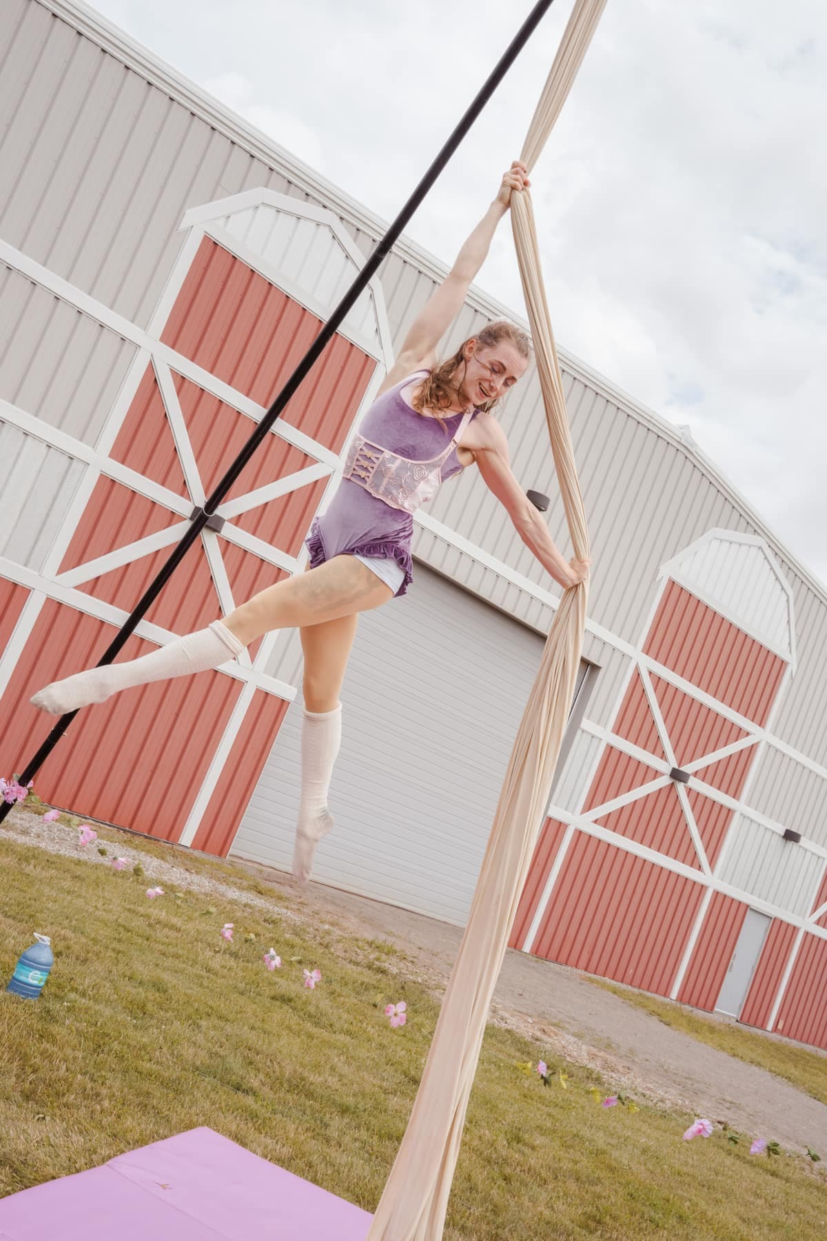 Kai performing on aerial silks outdoors beside the studio barn